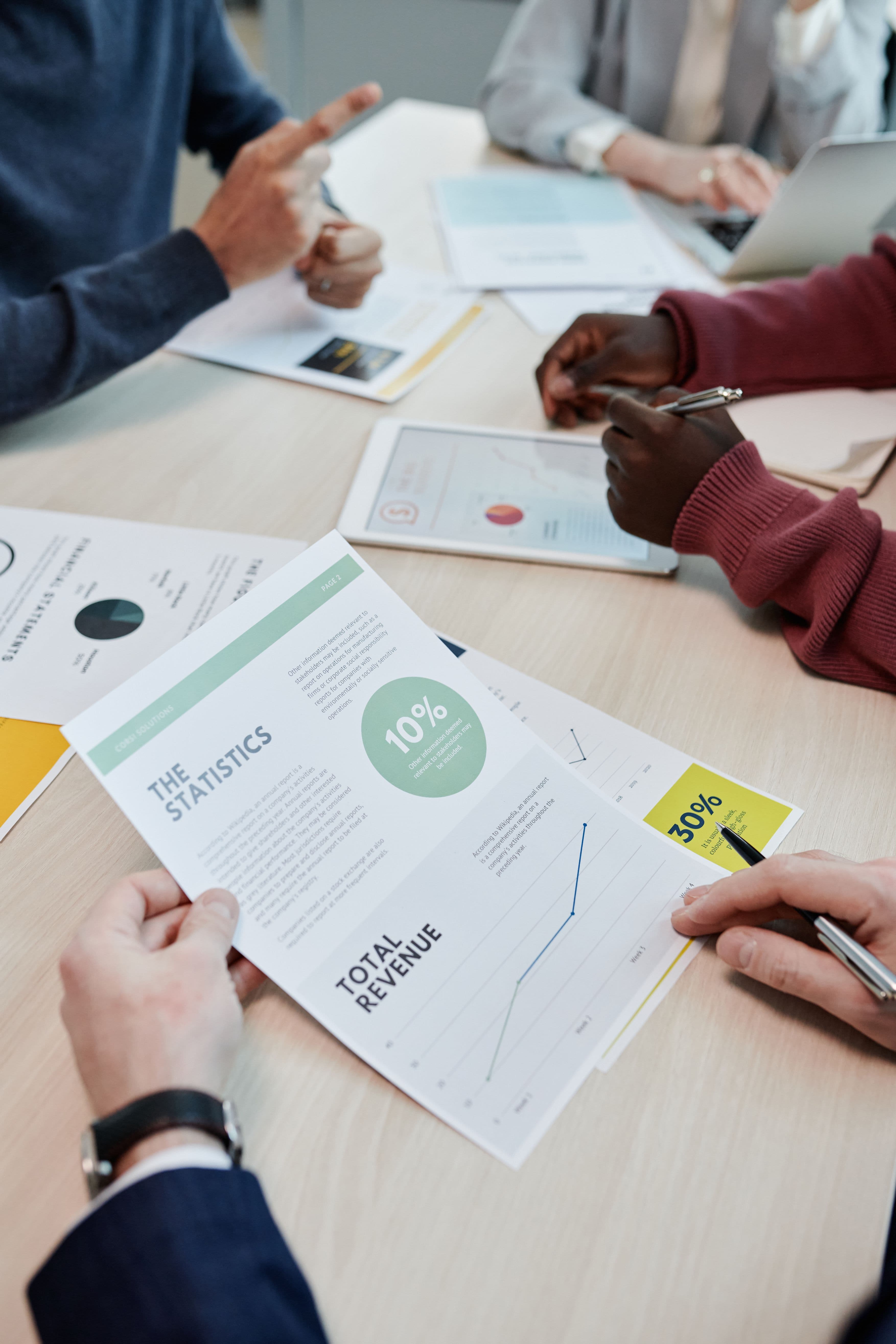 Team of professionals collaborating over financial reports and revenue charts